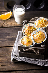 Cakes in a wooden box, a glass of milk on a wooden table.