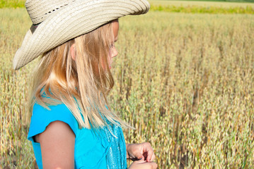 young Caucasian girl wearing western style hat in wheat field