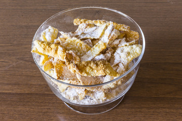 Sprinkle with powdered sugar, fried plate of shortcake dough. Dessert Polish and Lithuanian cuisine - faworki ( angel wings). Faworki in a large glass vase..