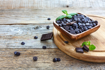 Bowl with black chocolate on a wooden cutting board.