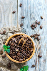 Roasted coffee beans and mint in a wooden bowl.