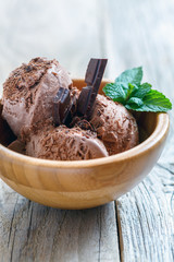 Homemade ice cream and dark chocolate in a wooden bowl.