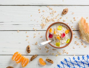 Cooked porridge oatmeal in a bowl on wooden white background. Ingredients for cooking.