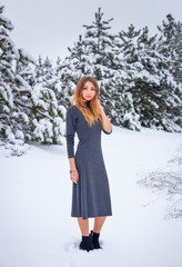 Pretty young girl posing in the winter in cold forest with pine