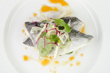 Dorado fish with grapefruit and green salad on a plate on a white background, closeup