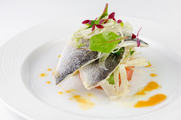 Dorado fish with grapefruit and green salad on a plate on a white background, closeup