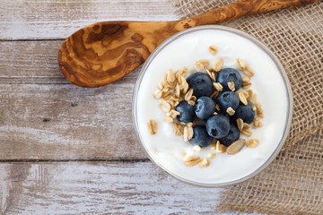 Yogurt with sweet blueberries and granola, above view on rustic wood