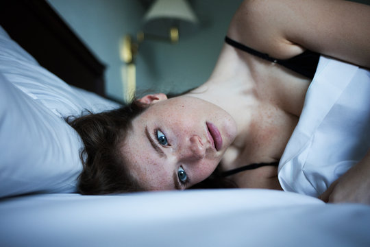 Portrait of pensive and sad woman in bed with green eyes