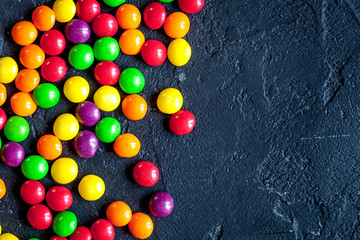 Fototapeta na wymiar sweets and sugar candies on dark background top view