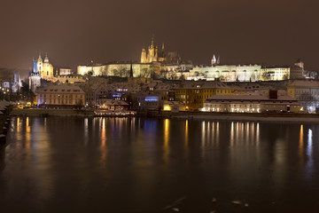 Fototapeta na wymiar Night snowy Prague Lesser Town with gothic Castle above River Vltava, Czech republic