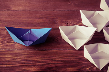 Business leadership concept with white and color paper boats on 
