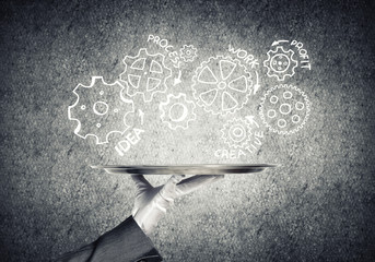 Waiter hand with empty silver tray and drawn gears concept