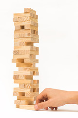 Tower of wooden blocks Jenga game and man's hand