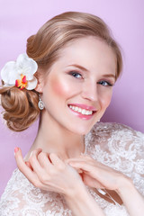 Obraz na płótnie Canvas Beautiful bride with fashion wedding hairstyle - on pink background.Closeup portrait of young gorgeous bride. Wedding. Studio shot.