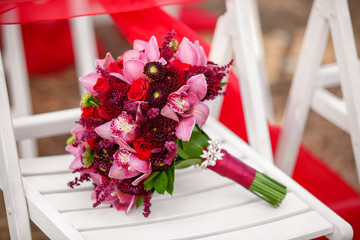 Red wedding bouquet of orchid flowers outdoor ceremony. Bride flowers