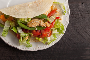 Chicken fajitas with lettuce and tomatoes above shot