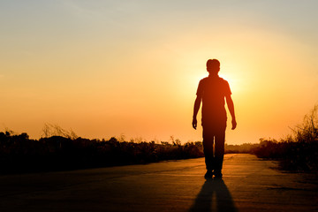 silhouette man walking on road at sunset background