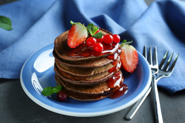 Delicious pancakes decorated with berries and blue napkin on table