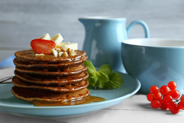 Closeup of blue plate with delicious chocolate pancakes decorated with strawberry and banana