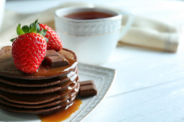 Plate with delicious chocolate pancakes with strawberry on served table