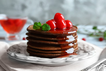 Plate with delicious chocolate pancakes and berries on table