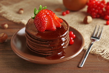 Delicious chocolate pancakes with strawberry on served table