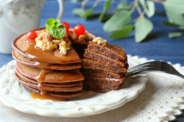 Tasty chocolate pancakes with  viburnum and nuts on white plate