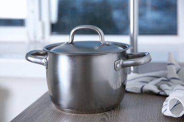 Stainless saucepan on grey kitchen table, closeup