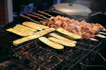 Street food. Grilled zucchinis and chicken meat roasted on skewers are on food stall. Christmas fair in Ukraine