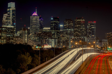 A long exposure of the Philadelphia skyline, with light trails from the freeway below