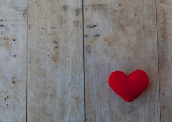 Red heart is placed on a wooden floor.