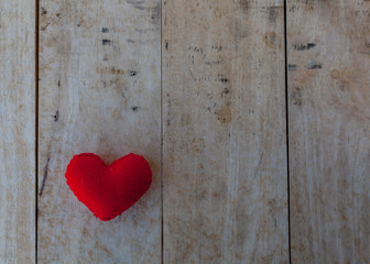 Red heart is placed on a wooden floor.