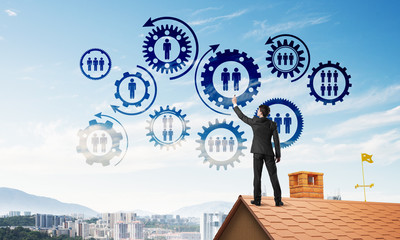 Businessman on house roof presenting teamwork and connection concept. Mixed media