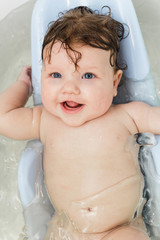 Little baby swims in the bathtub and laughs.