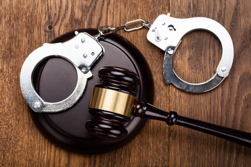 Gavel And Handcuffs On Wooden Desk