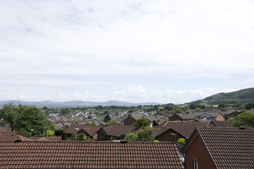 Roof tops of village in Britain with surrounding countryside, mountains, hills and blue sky and clouds 2 of 2