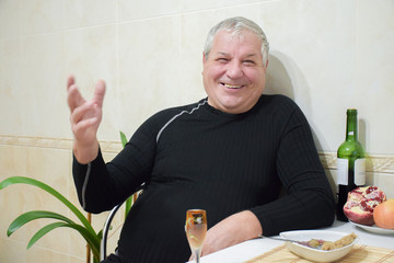 Old caucasian man drinking wine at home