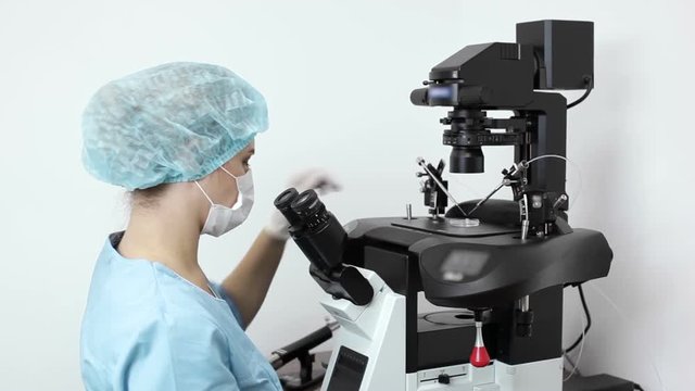 Embryologist performing in vitro fertilization icsi procedure on micromanipulator in lab