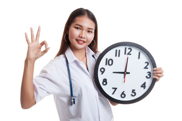 Young Asian female doctor show OK with a clock.