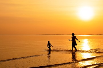 Mother and daughter playing on the beach at sunset