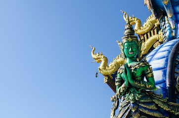 Fototapeta na wymiar Thai Tradition Green Male Angel Sawasdee (Hello) with Blue Sky at Wat Rong Sua Ten Chiang Rai Thailand. Most Visited from Tourist.