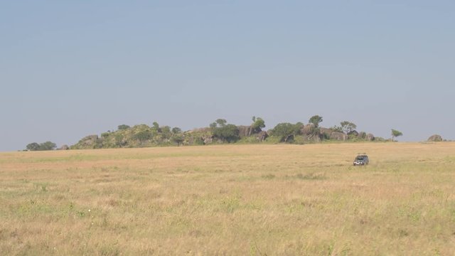 Off-road safari jeep game driving past stunning rocky outcrop called kopje