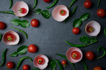 Fresh tomatoes in cracked eggshell on black stone background