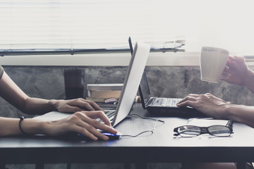 Coworkers working on the same desk, they are using a laptop