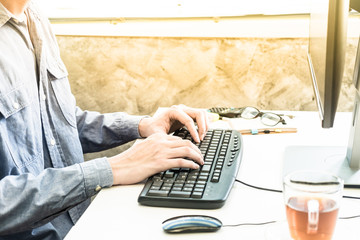 Fototapeta premium Close up of Male hands typing on desktop computer keyboard 