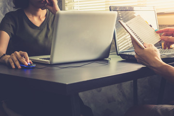 Coworkers working on the same desk, they are using a laptop