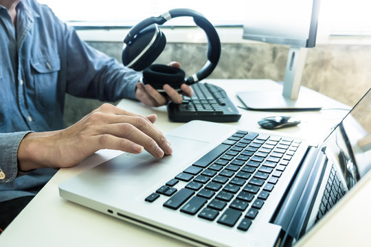 Male Hands Holding Headphones And Working On Computer