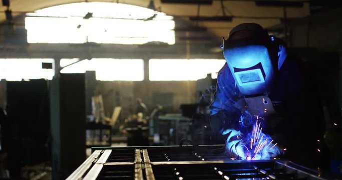 .A blacksmith or welder, with his welder, welding steel and iron, in extreme slow motion. The welder uses a mask to protect your eyes from sparks. concept: manual work, blacksmith, industry, welder