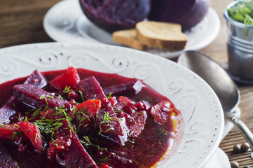 Vegetable soup - red borsch  in a white bowl on a rustic wooden background, clouse up. Healthy beetroot soup, vegetarian food. Delicious beet soup with croutons.