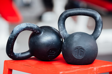 Large cast-iron sixteen pound weight dumbbell on gym .